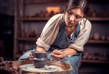 Beautiful ceramist making ceramic pot on the pottery wheel . Handiwork.