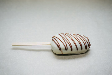 delicious cake like ice cream on a stick in icing and chocolate on a napkin