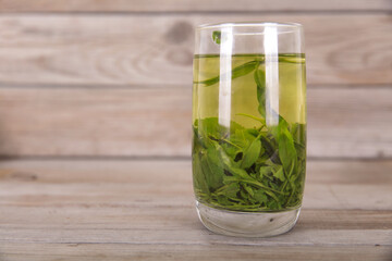 A cup of freshly brewed green tea on a wooden table