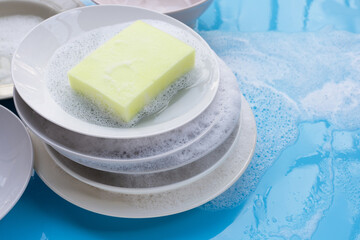 Washing dishes concept. wet blue with soapy foam background.