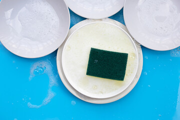 Washing dishes concept on wet blue background. Top view
