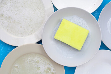 Washing dishes concept on wet blue background. Top view