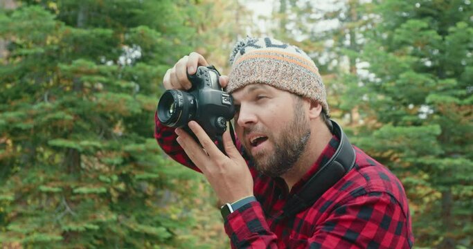 Young bearded man in a hat with a camera taking pictures of early fall nature 4K