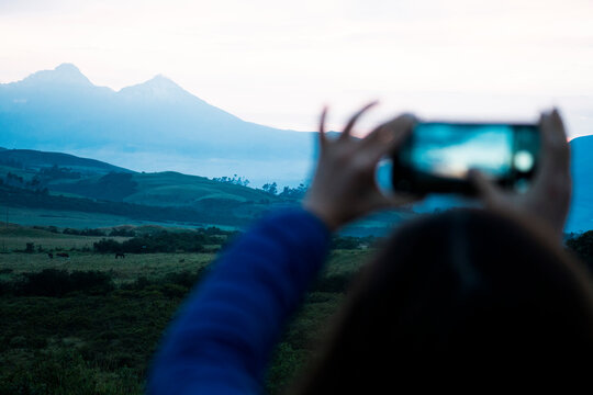Woman taking photograph at sunset in the mountains
