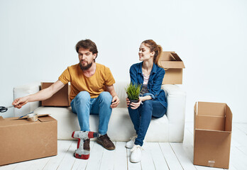 Fototapeta na wymiar A man and a woman are sitting on the couch near the boxes with things moving the interior of the room