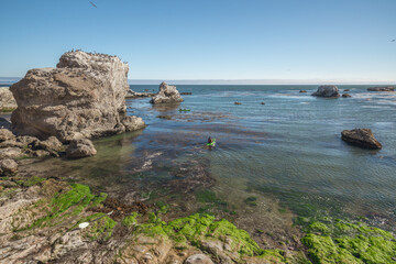 Fototapeta na wymiar Sea kayaking overlooking Pacific ocean, rocky cliffs and caves, California coastline