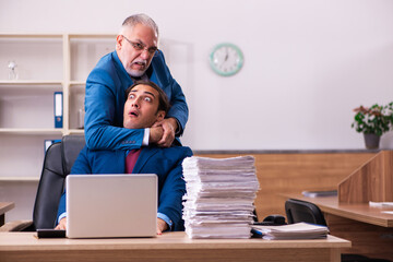 Old male boss and his young male assistant in bullying concept