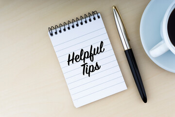 HELPFUL TIPS text with fountain pen and cup of coffee on wooden background. Business and copy space concept..