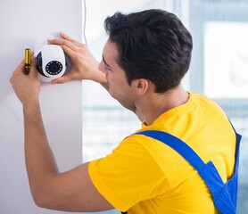 Contractor installing surveillance CCTV cameras in office