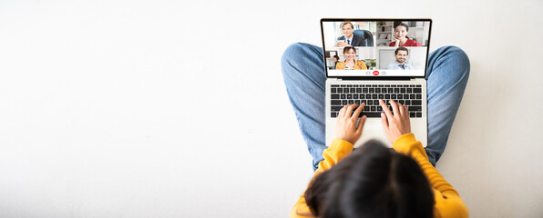 Top view of woman sitting on floor and using laptop video call conference her team. Panoramic image with empty copy space - obrazy, fototapety, plakaty