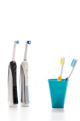 Professional Electric Toothbrushes In Front of Two Manual Tooth Brushes in One Cup On White