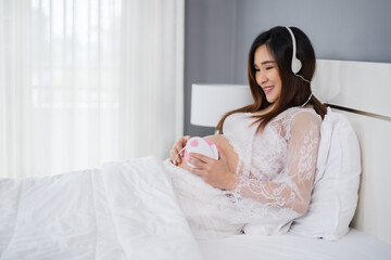 Obraz na płótnie Canvas pregnant woman listening to fetal heart sound through headphones on bed