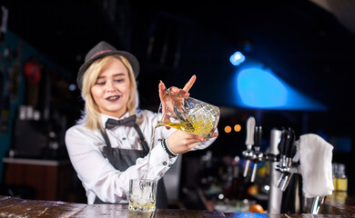 Girl bartender mixes a cocktail in the alehouse