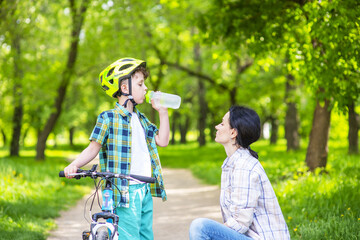 Mom explains to the child how important it is to drink enough water while cycling.