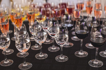 Line of alcohol setting on catering banquet table, bartender pouring beverages, row of different colored alcohol cocktails on a party, martini, vodka, and others on decorated banquet table event