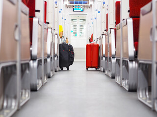 Red luggage and black bag put on walkway beside passenger in the train.