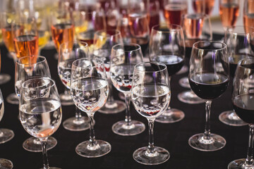 Line of alcohol setting on catering banquet table, bartender pouring beverages, row of different colored alcohol cocktails on a party, martini, vodka, and others on decorated banquet table event
