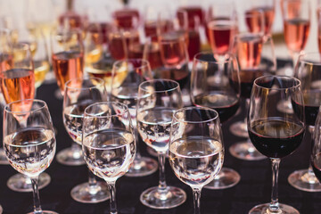 Line of alcohol setting on catering banquet table, bartender pouring beverages, row of different colored alcohol cocktails on a party, martini, vodka, and others on decorated banquet table event