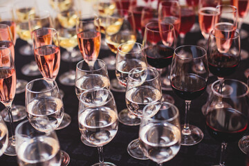 Line of alcohol setting on catering banquet table, bartender pouring beverages, row of different colored alcohol cocktails on a party, martini, vodka, and others on decorated banquet table event