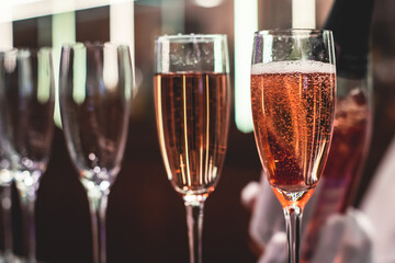 Line of alcohol setting on catering banquet table, bartender pouring beverages, row of different colored alcohol cocktails on a party, martini, vodka, and others on decorated banquet table event