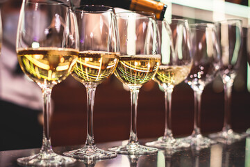 Line of alcohol setting on catering banquet table, bartender pouring beverages, row of different colored alcohol cocktails on a party, martini, vodka, and others on decorated banquet table event