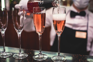 Line of alcohol setting on catering banquet table, bartender pouring beverages, row of different colored alcohol cocktails on a party, martini, vodka, and others on decorated banquet table event