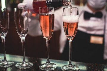 Line of alcohol setting on catering banquet table, bartender pouring beverages, row of different colored alcohol cocktails on a party, martini, vodka, and others on decorated banquet table event