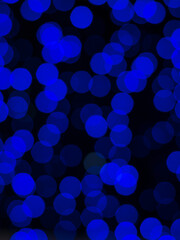 Blurry background of bright blue bokeh on black.