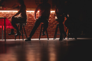 View of pub interior with people silhouettes drinking alcohol beverages and chatting at the bar counter, backlit illumination