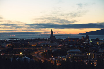 Beautiful night dusk view of Reykjavik, Iceland, aerial view with Hallgrimskirkja lutheran church, with scenery beyond the city, Esja mountain and Faxafloi bay