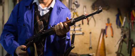 Fototapeta na wymiar Closeup of Kalashnikov assault rifle in hands of gunsmith. Professional firearms maintenance concept