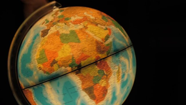 man spinning old vintage 80s globe to reach Africa 4k