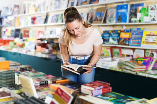 Portrait of smiling young woman buying textbooks in book store