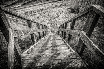Old wooden staircase going to the river bank. Black and white photo.