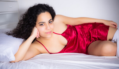 Naklejka premium Portrait of sexy brunette woman in red lingerie enjoying lying in bed