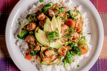 Delicious shrimp teriyaki with broccoli, pumpkin, carrot and rice in oyster sauce on a white plate.