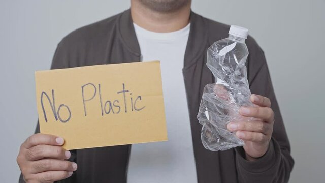 A man was raising a dented plastic bottle and a sign that reads No Plastic. World environment day.4K Resolution.
