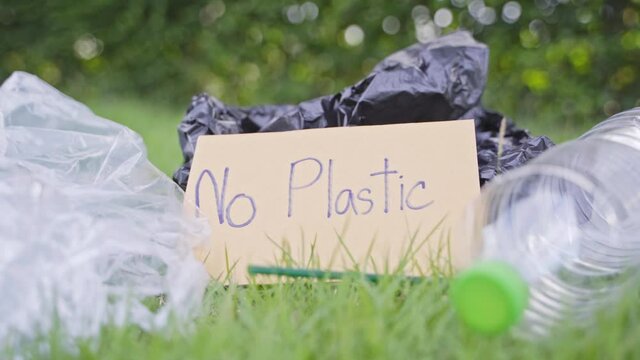 Many plastic waste piles on the lawn. And there is a sign that says do not throw plastic waste.4K Resolution.
