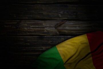 wonderful dark image of Mali flag with big folds on old wood with free place for text - any occasion flag 3d illustration..