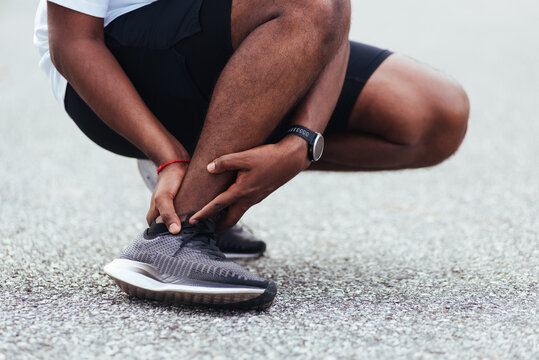 Close up Asian young sport runner black man wear watch hands joint hold leg pain because of twisted ankle broken while running at the outdoor street health park, healthy exercise Injury from workout