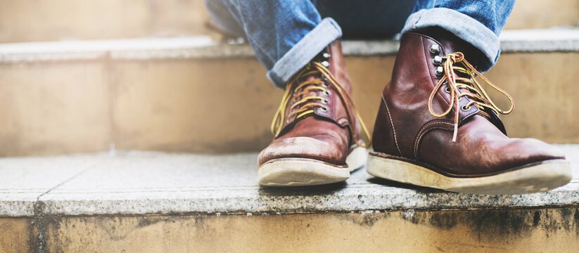 Close up image of young hipster wearing blue jeans and shoes leather sitting at city stairs during travel destination to grow and learn experience.