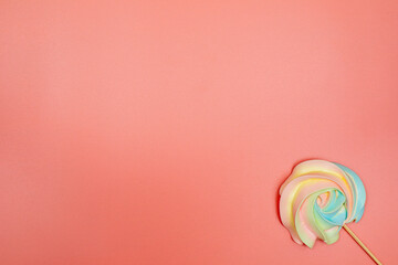 Fototapeta na wymiar Rainbow meringue on a stick on a pink background. Christmas, New Year, Valentine's Day, International Women's Day or Mother's Day composition. Flat lay with copy space.