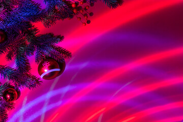 Christmas ornament and fir branches on a red festive background in neon light