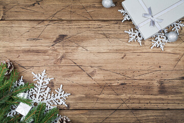 fir branches , gift , cones, snowflakes and balls on brown wooden background, top view flat lay copy space.