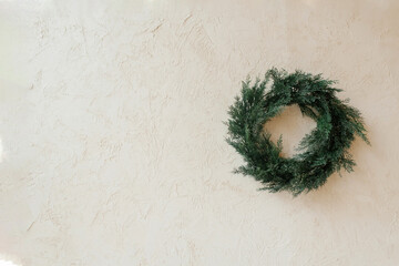Fototapeta premium Christmas wreath made of coniferous wood on a beige background with copying space