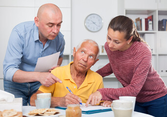 Mature father and adult children fill out paperwork. High quality photo