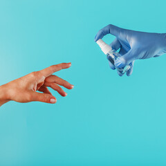 The hand is extended towards the gloved hand and the antiseptic spray in the blue glove on a blue background.