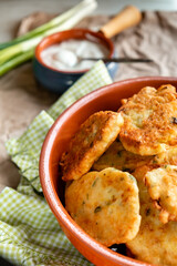 Pancakes with zucchini and cabbage with yoghurt dressing and herbs on the table by the window. Close up