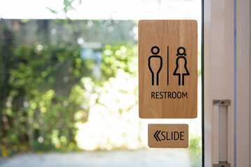 Toilets icon, Public restroom signs ,Wooden toilet sign and direction on glass door blurred background.
