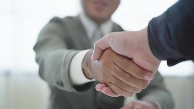 Businessmen agree to enter into a commercial contract between companies. He stood for a good deal and agreed by shaking hands.4K Resolution.
